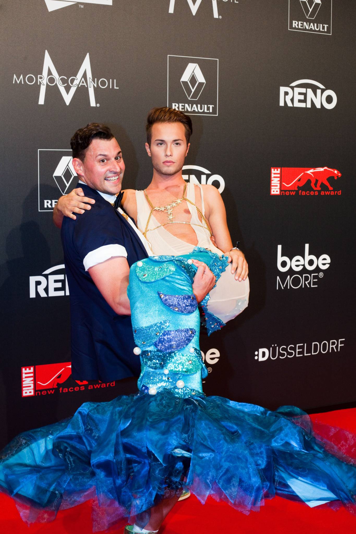 Mann hält anderen im Kostüm auf den Armen